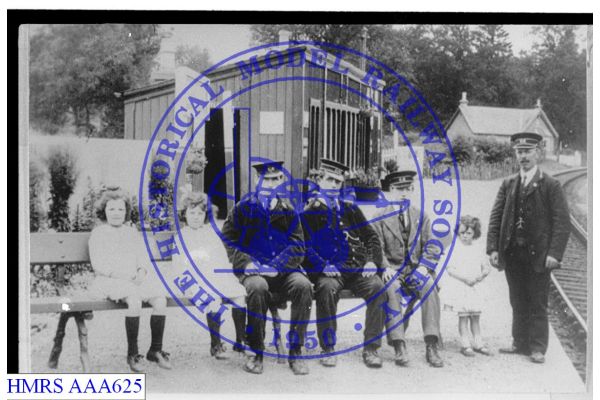 [AAA625] Posed group of station staff and children on Barnhill station seat Gentlemen's toilet behind, statio