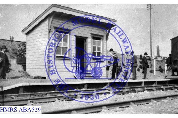 [ABA529] Kelvedon Low Level waiting room and platform ca1905 inc passengers Station signboard at back of plat
