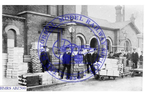 [ABZ500] Spalding, cartage staff posed in front of station with boxed flowers in several piles, 3 luggage  tr